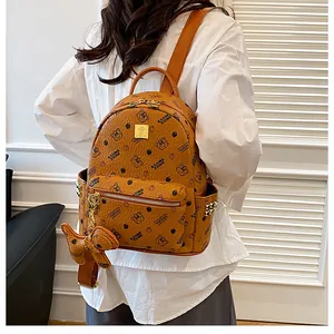 Détail d'un sac à dos marron avec imprimés ours et accents de clous métalliques dorés