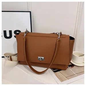 Detail of caramel leather handbag featuring silver twist lock and wide canvas strap
