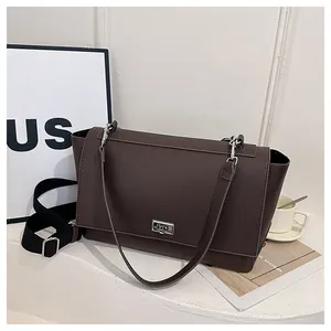 Detail of dark brown lychee pattern leather handbag with silver clasp and adjustable strap