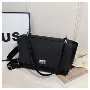 Macro detail of black litchi texture on crossbody bag with silver twist-lock closure