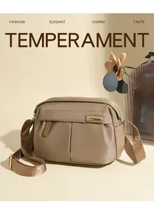 Detail of khaki oxford crossbody bag with metal zippers and textured nylon fabric