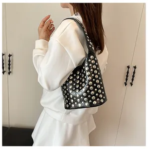 Detail einer schwarzen Leder-Eimertasche mit Silbernieten als Unterarm-Schultertasche