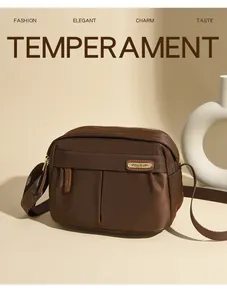 Close-up of brown Oxford fabric crossbody bag with adjustable strap and zip pockets
