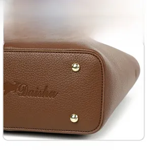Detail view of brown lychee grain leather handbag base with gold protective rivets