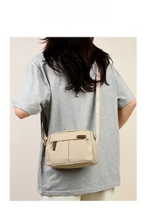 Detail of beige nylon crossbody bag featuring stylish pleated front and jacquard logo strap