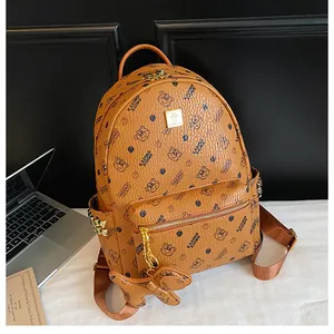 Détail d'un sac à dos en cuir marron avec imprimé ours et plaque logo en métal doré