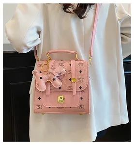 Detail of pink faux leather backpack with letter patterns and a cute dog charm