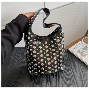 Detail der glänzenden schwarzen Hobo-Tasche mit Nieten und nahtlosem Handgriff