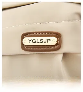 Detail of the golden metal logo plate on beige oxford fabric with neat stitching