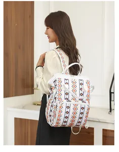 Vista detallada de la mochila maternal impermeable con patrones étnicos naranja y negro