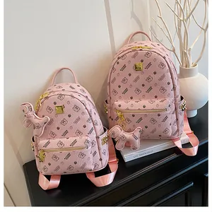 Détail de sacs à dos roses imprimés en deux tailles avec plaques dorées et pendentifs
