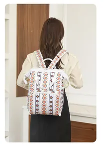 Vista trasera de una mochila para pañales con estampado tribal usada por una modelo