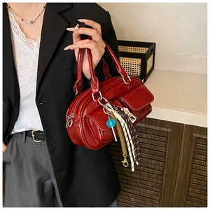 Close-up of deep red glossy pillow bag featuring dual front pockets and stylish charms