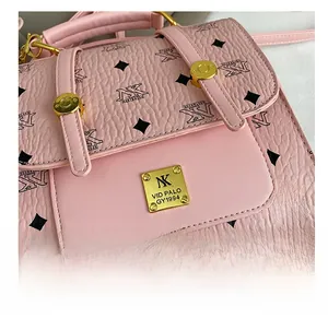 Close-up of pink textured pebbled leather with golden clasp and metal brand plate