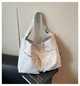 Detail of minimalist cream tote bag showing crinkled nylon texture and front pockets