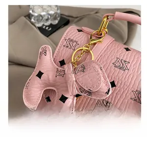 Close-up of pink pebbled leather backpack with a cute dog charm and golden hardware