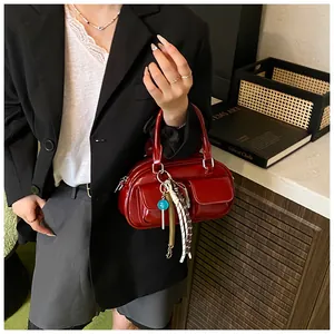 Detail of red patent leather pillow bag with double front pockets and creative charms