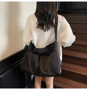 Detail of minimalist large black tote bag with two front pockets and wide shoulder strap