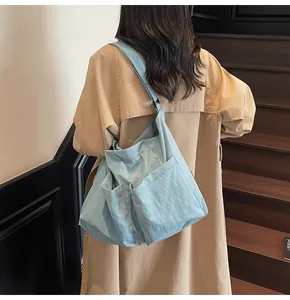 Detailed side view of light blue large capacity tote bag worn with a classic trench coat