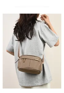 Detailed view of khaki oxford fabric crossbody bag on model with smooth zipper closure