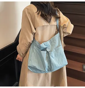 Detail of light blue nylon tote bag with double front pockets on khaki trench coat