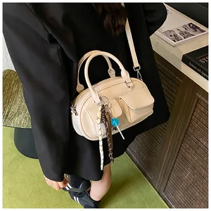 Detail view of beige pillow handbag with double front pockets and colorful bag charms