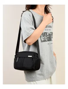 Close-up of black Oxford cloth bag with adjustable wide logo strap on a casual model
