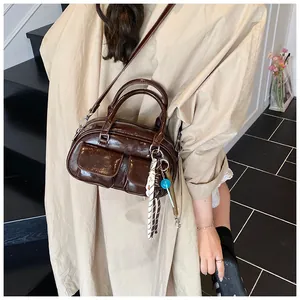 Detailed view of coffee brown patent leather bag with two front pockets on a model