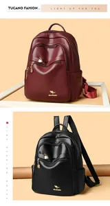 Detail of wine red and black leather backpacks with lychee texture and golden logo