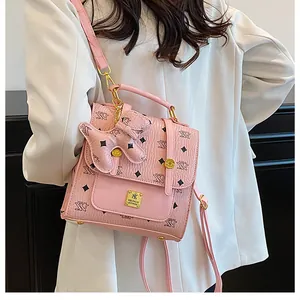Detailed side view of pink faux leather mini backpack with bear charm and golden logo