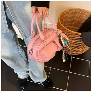 Detail of pink glossy patent leather Boston bag with dual pockets and decorative silk scarf