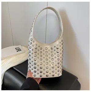 Nahaufnahme einer weißen Ledertasche mit Silbernieten und halbmodförmiger Silhouette