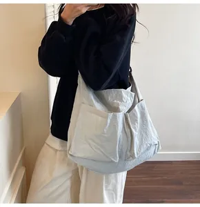 On-body shot of a large white minimalist tote bag showing practical size and nylon texture