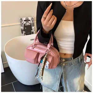 Pink Boston bag style handbag with twin flap pockets and decorative woven charms