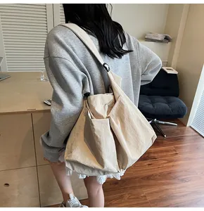 Detail shot of a large beige nylon tote bag showing soft folds and adjustable wide strap