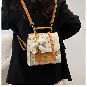 Detail of patterned mini backpack with dog charm and branded metal plate on front