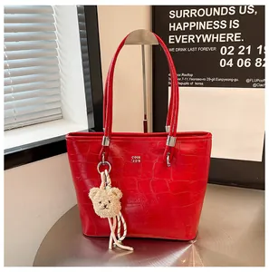 Détail d'un sac cabas rouge motif crocodile avec breloque ours et finitions argentées