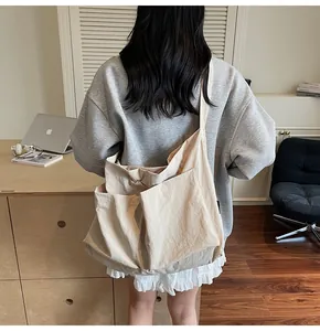 Close-up of beige canvas tote bag with front pockets on a person for casual daily use