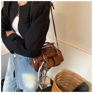 Detail of dark brown polished leather Boston bag with two front snap pockets and charms