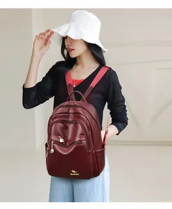 Detail of burgundy leather backpack with golden zippers and kangaroo logo for women