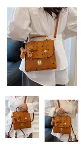 Detail of a brown printed faux leather bag with golden nameplate and a bear charm