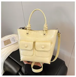 Detail of creamy yellow croc-effect handbag with double pockets and knotted handle
