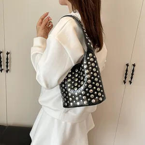 Modische schwarze Leder-Beuteltasche mit Silbernieten, getragen von einem Model im Zimmer