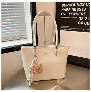Détail d'un sac cabas blanc à motif crocodile avec logo et breloque ours peluche