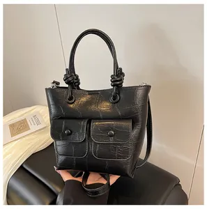 Detail of black crocodile texture handbag with dual front pockets and unique knot handle