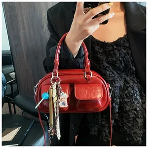 Detail of dark red boston bag featuring front flap pockets and creative decorative charms