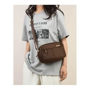 Brown nylon crossbody bag with multiple zip pockets shown on a model in a casual setting