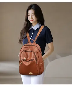 Close-up of brown textured leather backpack with multi-layer zippers and golden logo
