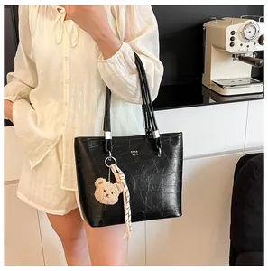 Détail du sac cabas noir à texture crocodile avec breloque ours sur mannequin en chemise