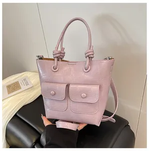 Detail of lilac crocodile embossed handbag showing knot handle and front pockets